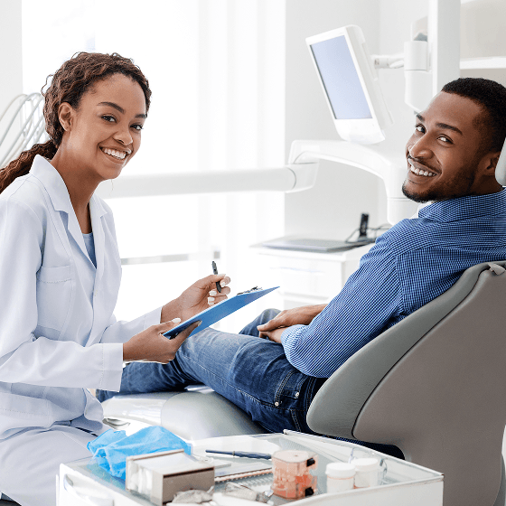 Smiling dentist reviewing notes with a patient in the dental chair